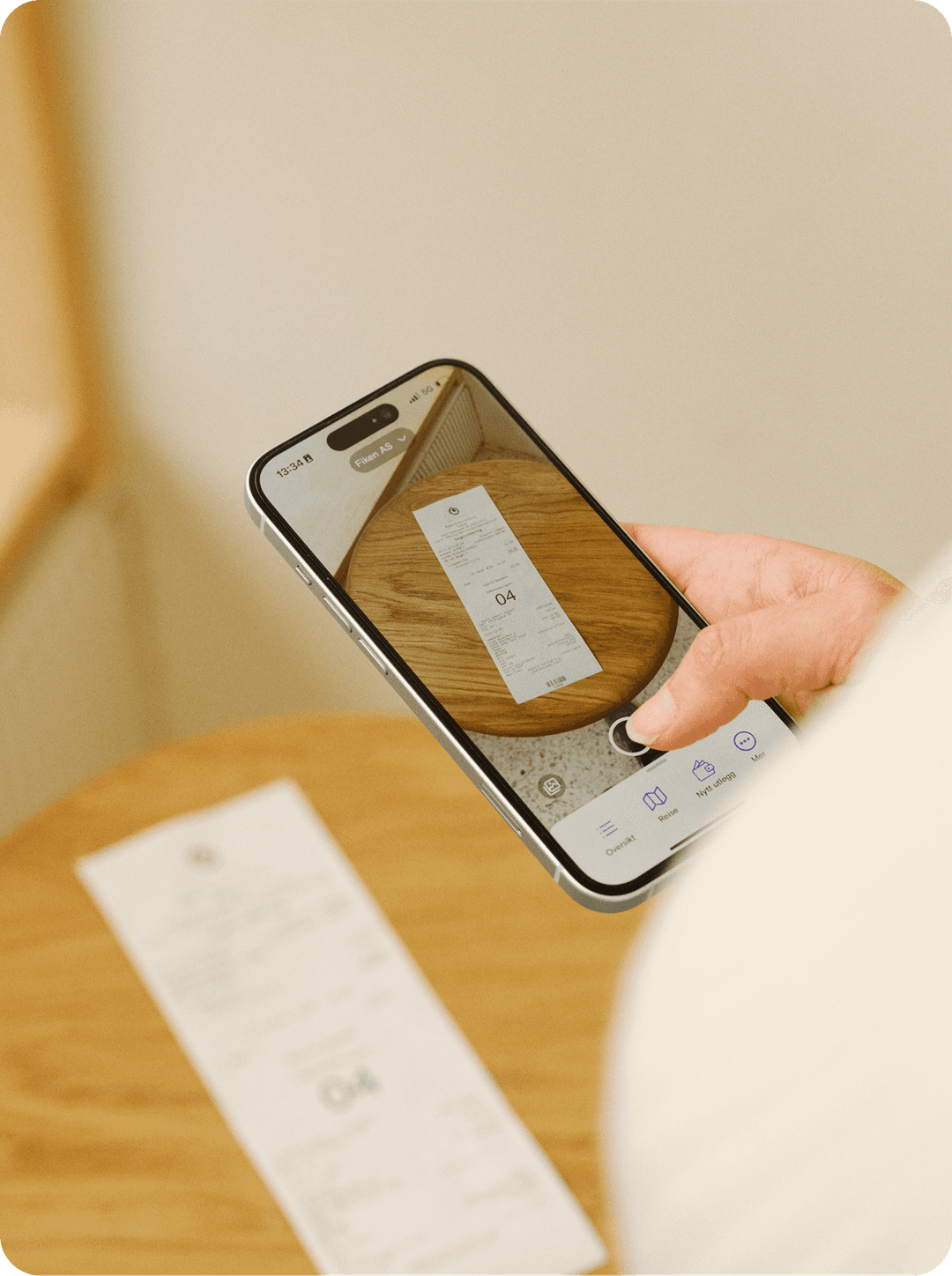 En bruker som tar bilde av kvitteringen sin med Fiken app